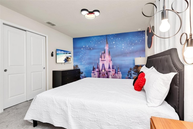 carpeted bedroom with an accent wall, a closet, and visible vents