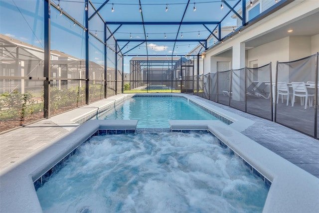 view of swimming pool featuring a lanai, a pool with connected hot tub, and a patio