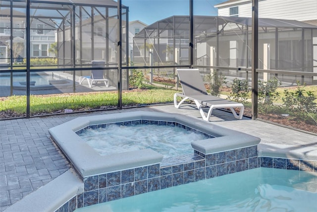 outdoor pool featuring an in ground hot tub, a patio area, and glass enclosure