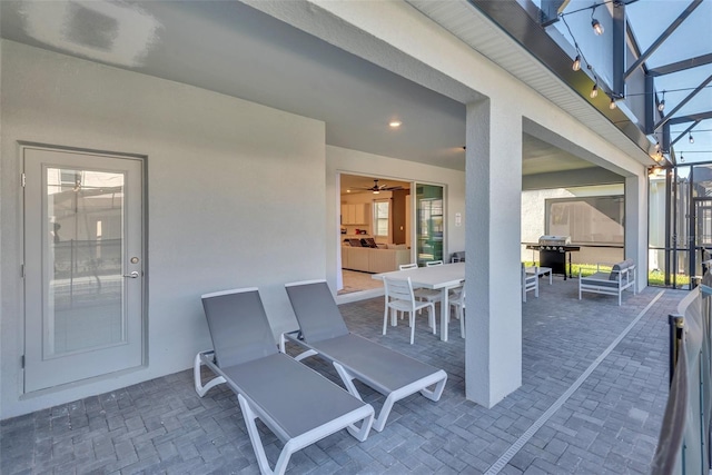 view of patio with glass enclosure, outdoor dining area, and area for grilling