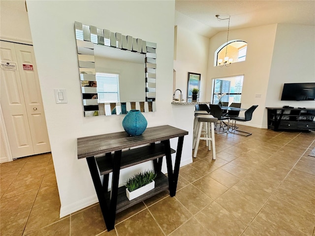 interior space featuring baseboards, high vaulted ceiling, and a notable chandelier