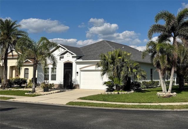 view of front facade featuring an attached garage, concrete driveway, roof with shingles, stucco siding, and a front yard