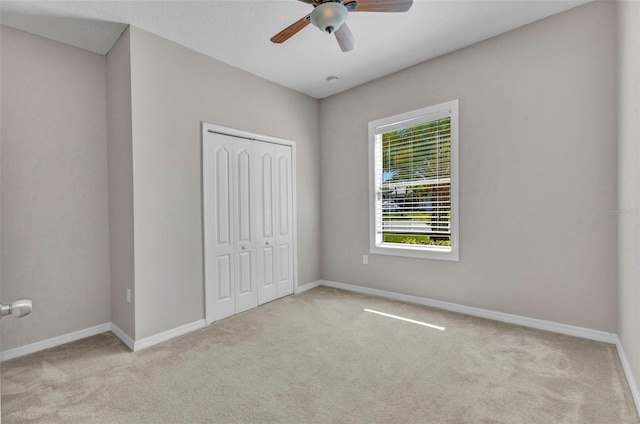 unfurnished bedroom with carpet, a closet, ceiling fan, and baseboards