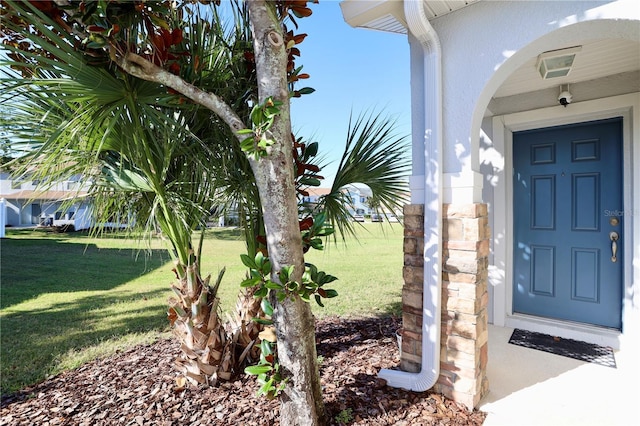 property entrance with a lawn and stucco siding