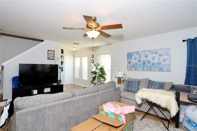 living area with visible vents, a textured ceiling, and a ceiling fan