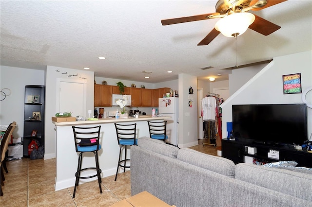 living room featuring light tile patterned floors, visible vents, a textured ceiling, and recessed lighting