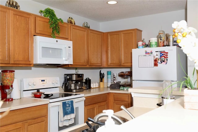 kitchen featuring white appliances, light countertops, brown cabinets, and a textured ceiling