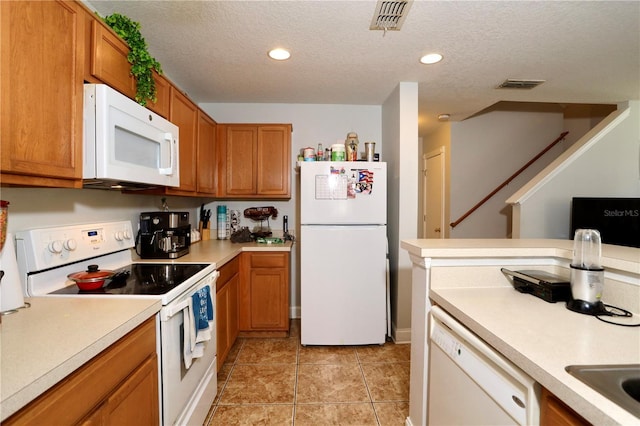 kitchen with brown cabinetry, visible vents, white appliances, and light countertops