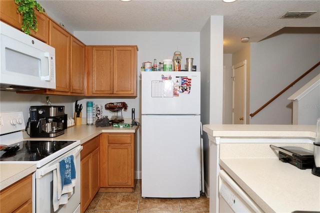 kitchen with visible vents, white appliances, a textured ceiling, and light countertops