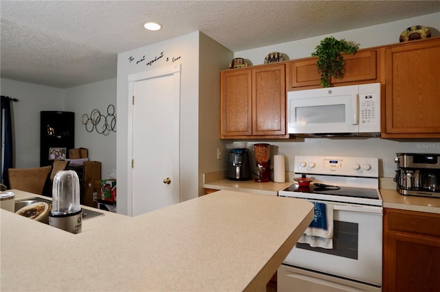 kitchen with brown cabinets, white appliances, a textured ceiling, and light countertops