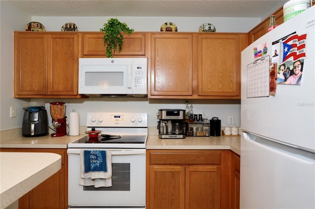 kitchen featuring brown cabinets, white appliances, a textured ceiling, and light countertops