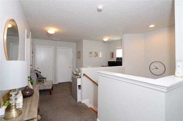 corridor featuring an upstairs landing, carpet, and a textured ceiling