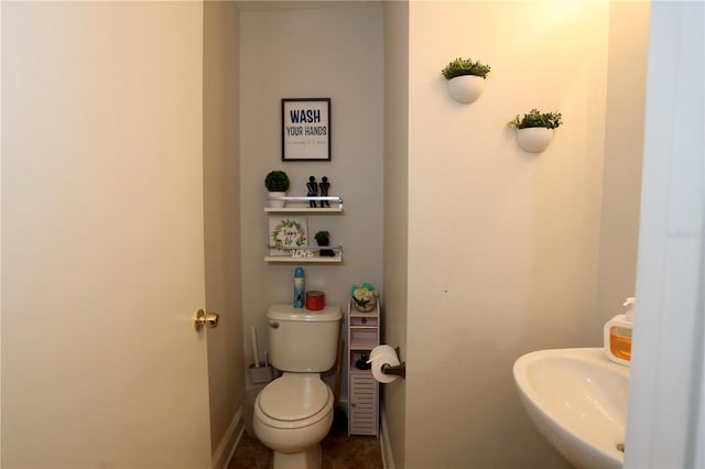 bathroom featuring toilet, baseboards, and a sink