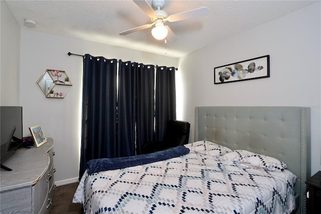 bedroom with dark carpet, a textured ceiling, baseboards, and a ceiling fan