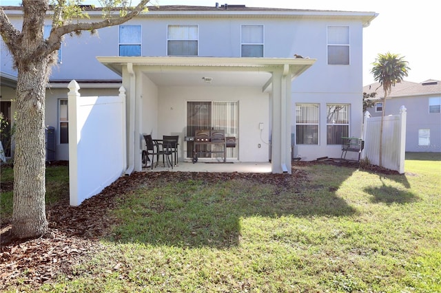 rear view of property with stucco siding, a patio, and a lawn