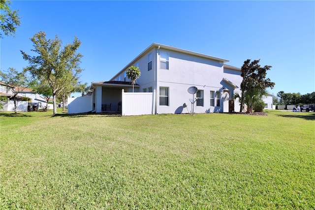 rear view of property featuring a lawn and stucco siding