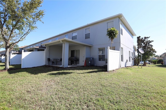 rear view of property featuring stucco siding, a patio, a lawn, and fence