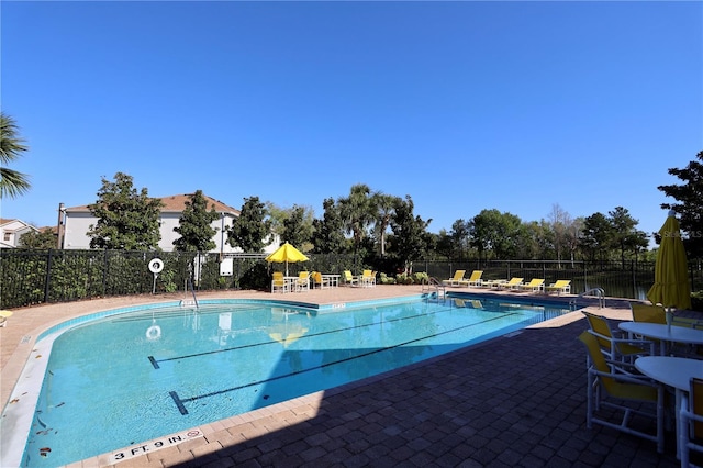 community pool with a patio and fence