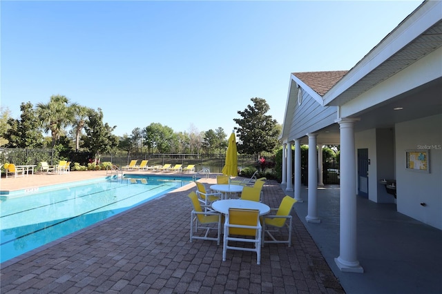 community pool with a patio and fence