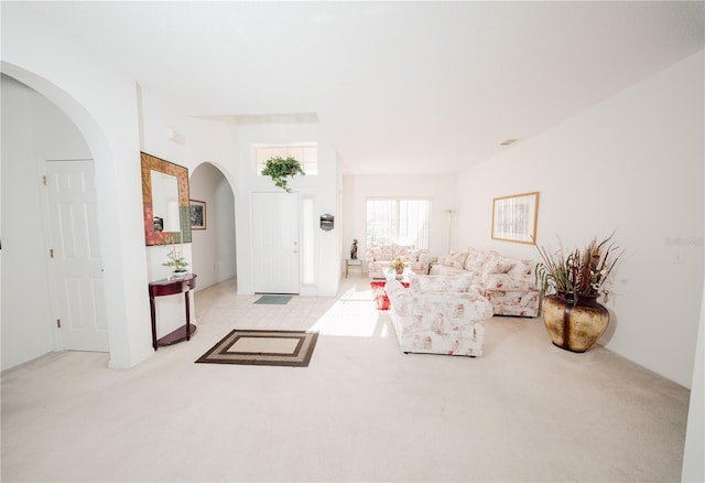 carpeted living area featuring arched walkways