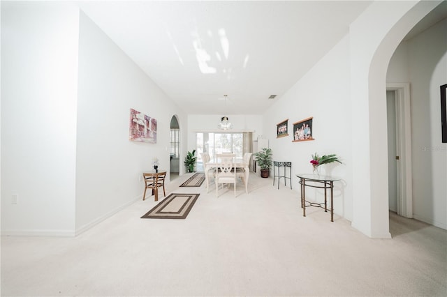 living area featuring visible vents, light carpet, a notable chandelier, arched walkways, and baseboards