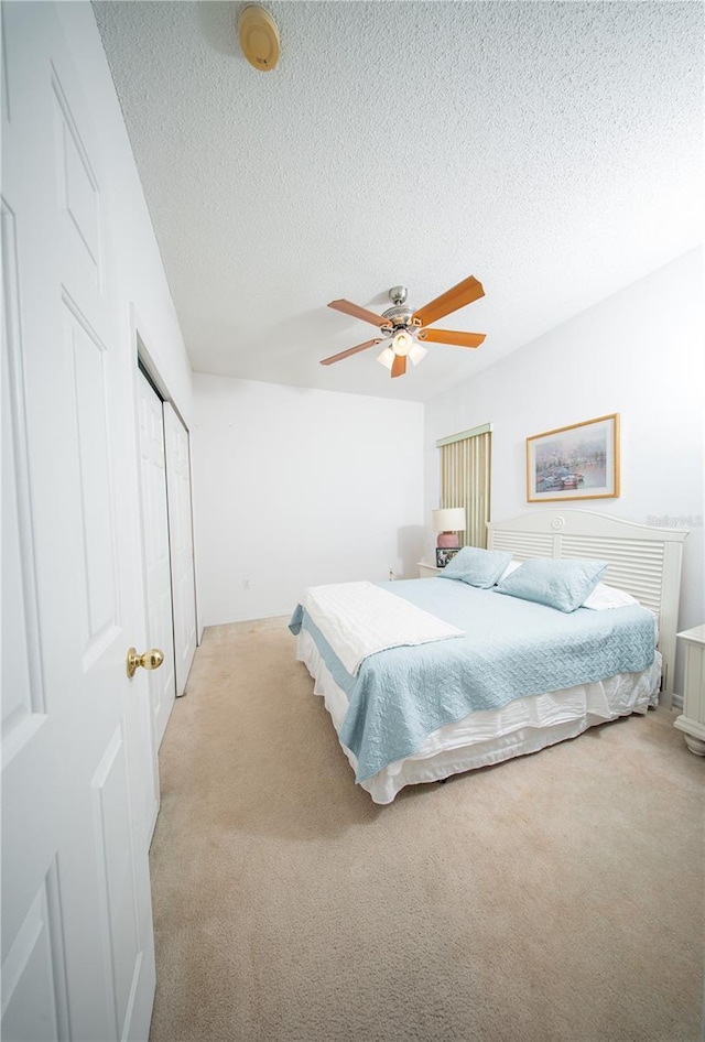 bedroom with a textured ceiling, a closet, and light carpet