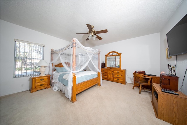 bedroom featuring light colored carpet, a textured ceiling, and ceiling fan