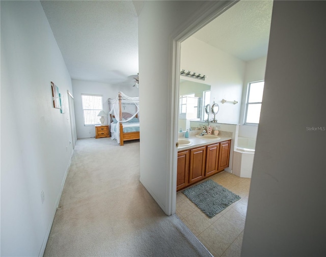 full bath with double vanity, a textured ceiling, ceiling fan, and a sink