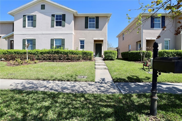 view of front of house featuring stucco siding and a front lawn