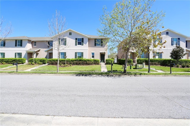 townhome / multi-family property featuring a front yard and stucco siding