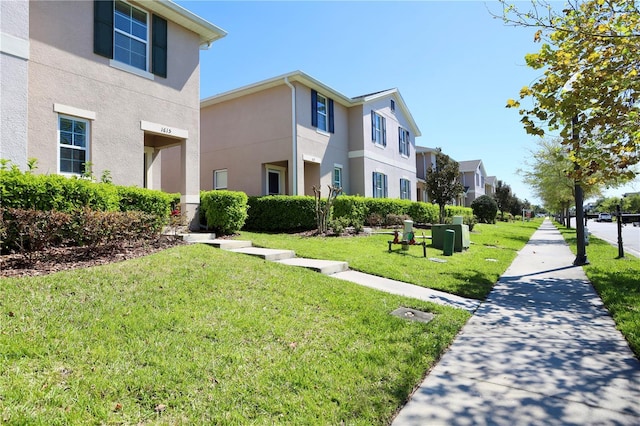 exterior space featuring stucco siding, a residential view, and a yard