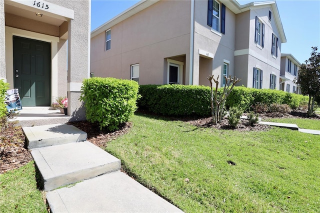 view of property exterior featuring stucco siding, a residential view, and a lawn