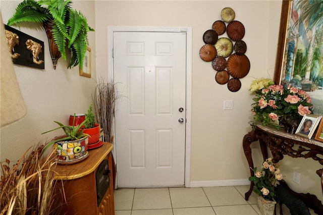 doorway with light tile patterned floors and baseboards