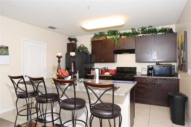 kitchen with under cabinet range hood, visible vents, black appliances, and a breakfast bar area