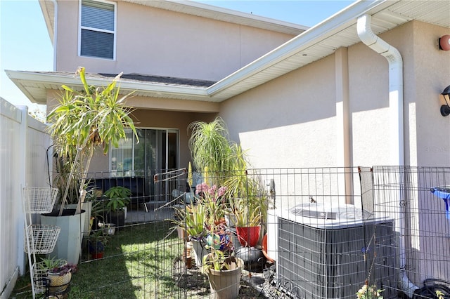 exterior space featuring central air condition unit, stucco siding, and fence