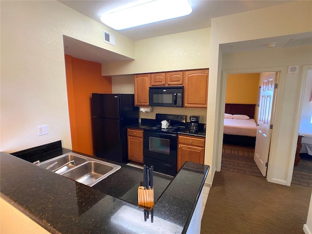 kitchen featuring visible vents, brown cabinets, a peninsula, black appliances, and a sink