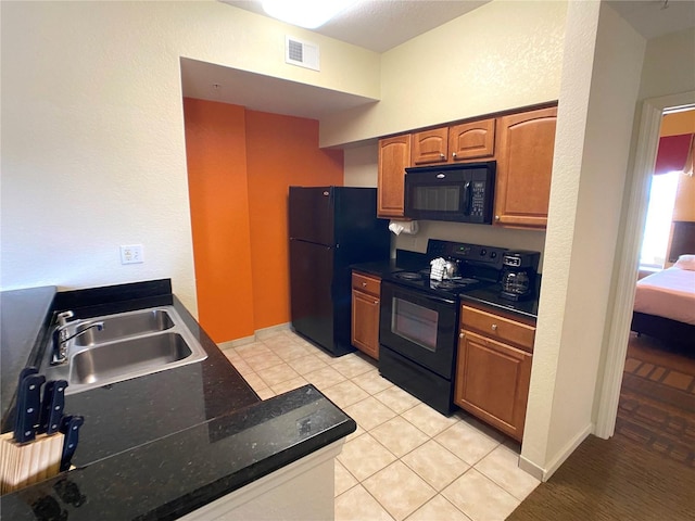 kitchen featuring visible vents, dark countertops, brown cabinets, black appliances, and a sink