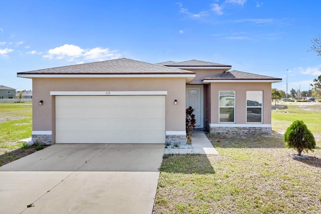 prairie-style home with driveway, a garage, stone siding, a front lawn, and stucco siding