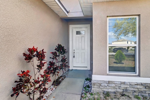 doorway to property featuring stone siding and stucco siding