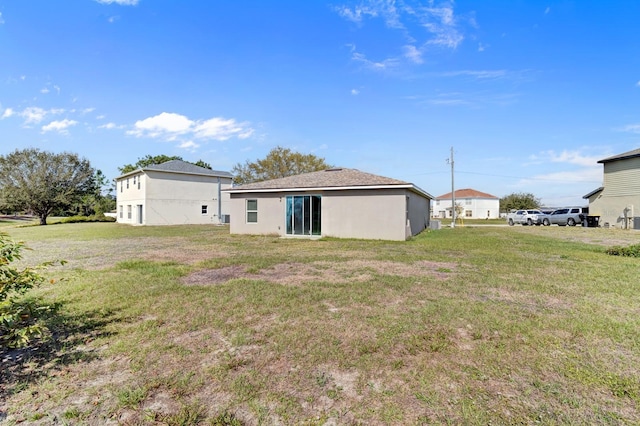 back of house with a yard and stucco siding