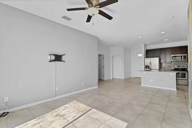 unfurnished living room featuring light tile patterned floors, visible vents, ceiling fan, a sink, and baseboards