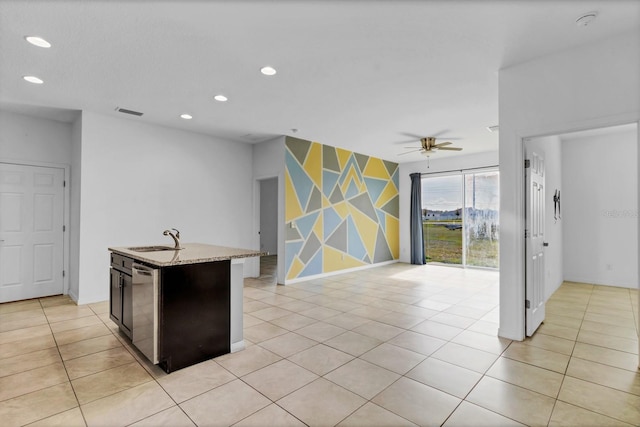 kitchen featuring light tile patterned floors, an accent wall, a sink, stainless steel dishwasher, and recessed lighting