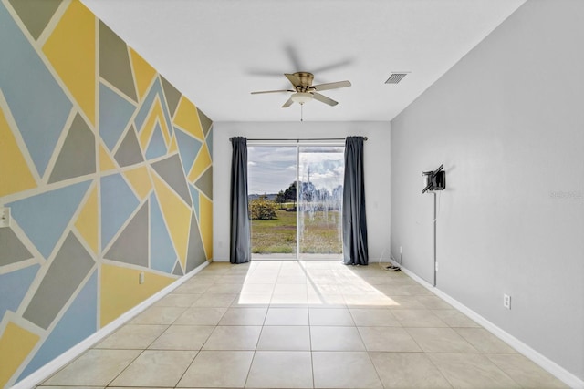 empty room with baseboards, visible vents, a ceiling fan, an accent wall, and tile patterned flooring