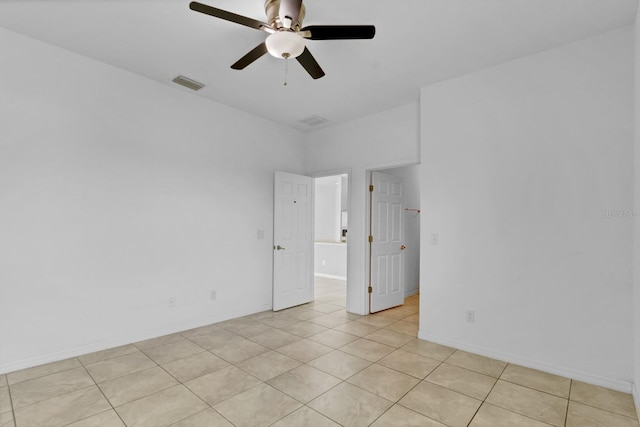 empty room featuring ceiling fan, light tile patterned flooring, visible vents, and baseboards