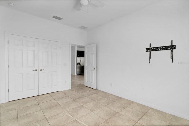 unfurnished bedroom featuring a closet, visible vents, ceiling fan, and light tile patterned floors