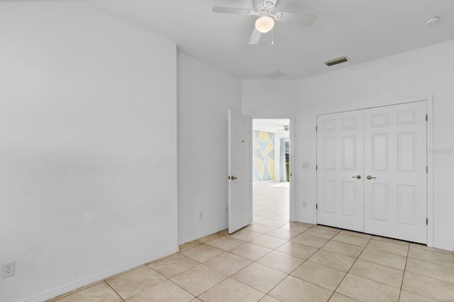 empty room with a ceiling fan, visible vents, baseboards, and light tile patterned floors