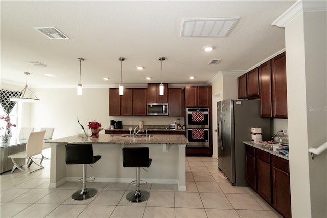 kitchen featuring light tile patterned flooring, visible vents, a kitchen breakfast bar, ornamental molding, and appliances with stainless steel finishes