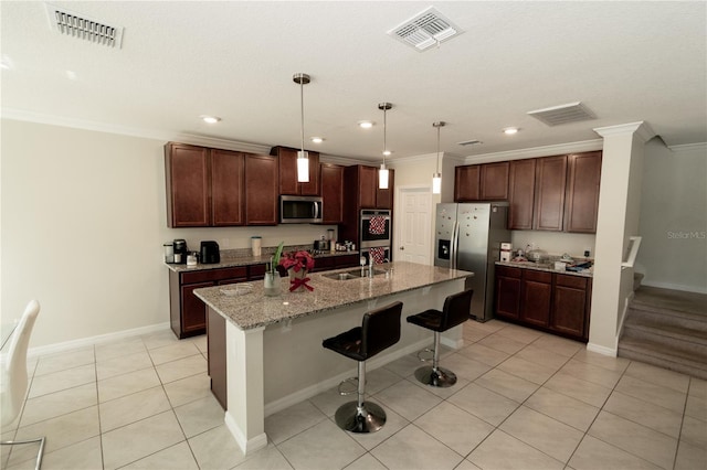 kitchen featuring stainless steel appliances, visible vents, a sink, and a kitchen breakfast bar