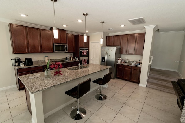 kitchen with light tile patterned floors, visible vents, a kitchen breakfast bar, stainless steel appliances, and a sink