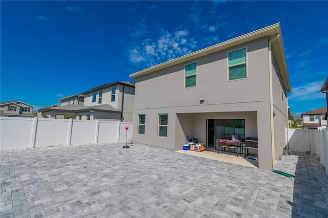 back of house featuring a fenced backyard, a patio, and stucco siding